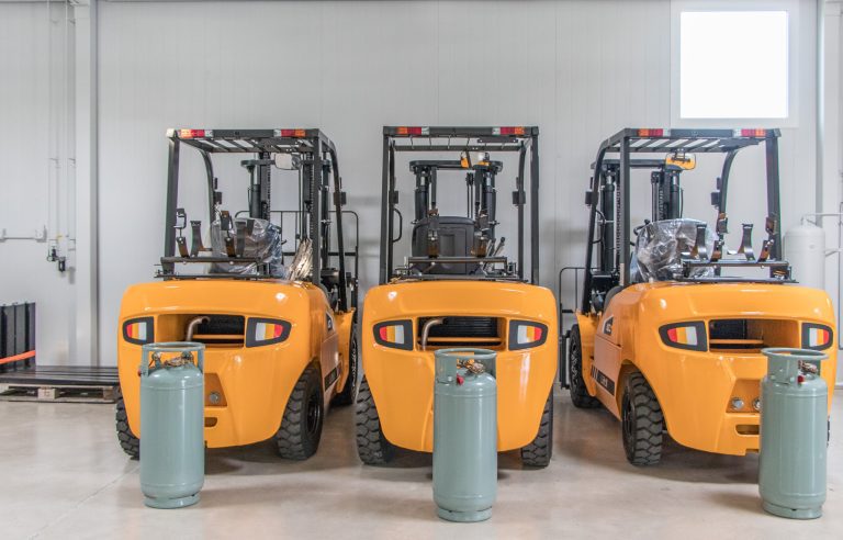 Three PowerLiftX Forklifts view from back with LPG Tanks on the ground.